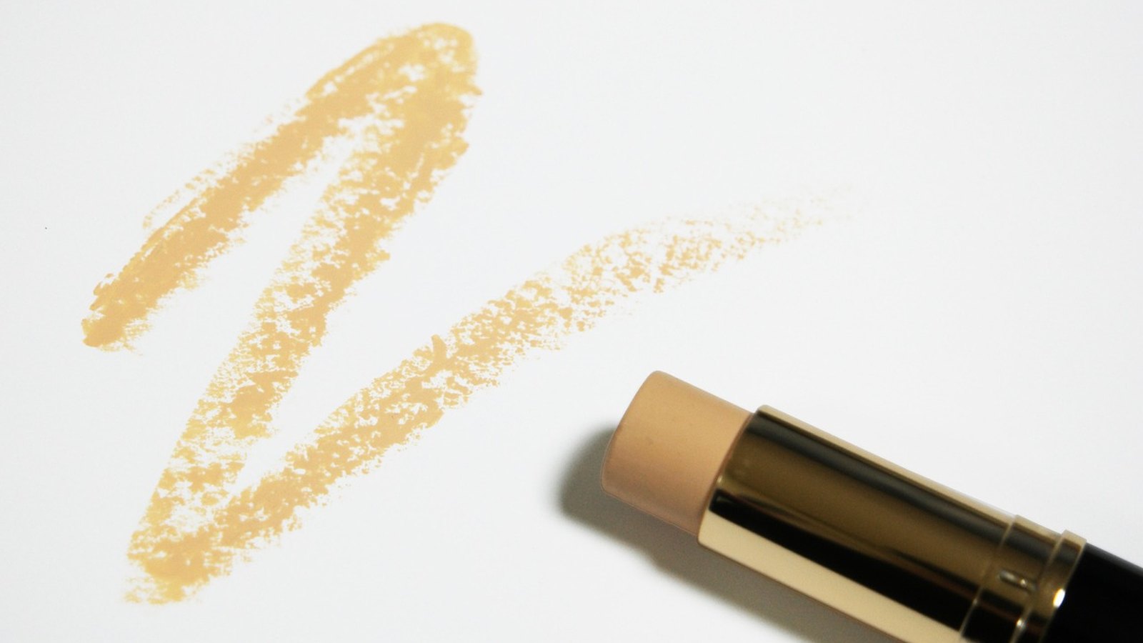 Tyčinkový make-up a béžová stopa po ňom na bielom podklade