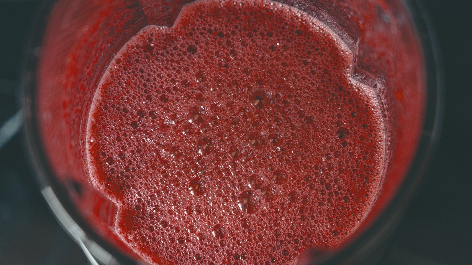 Pohľad do nádoby mixéra s červeným ovocným smoothie