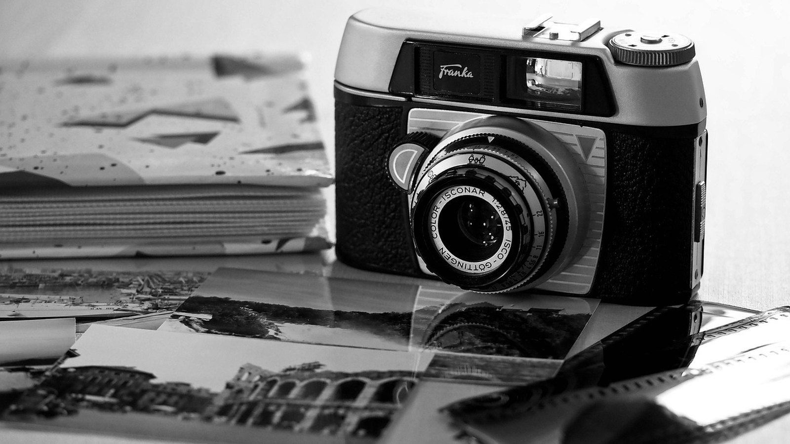 Starý fotoaparát s objektívom položený na čiernobielych fotografiách