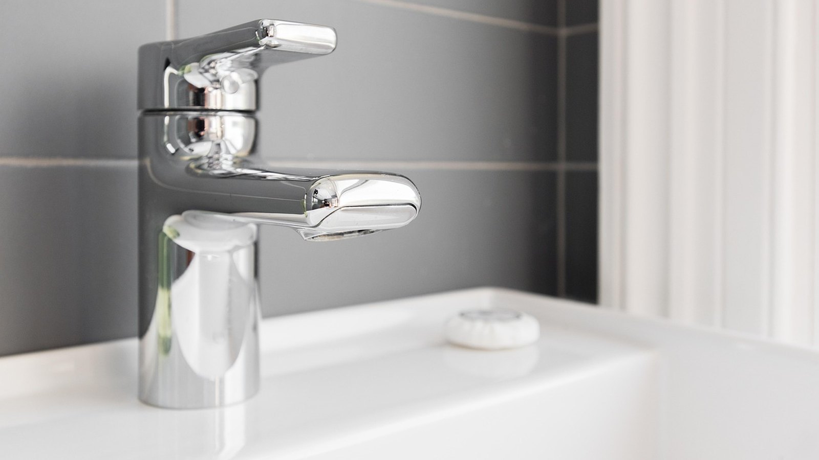 Lesklá chrómová páková batéria nad bielym umývadlom