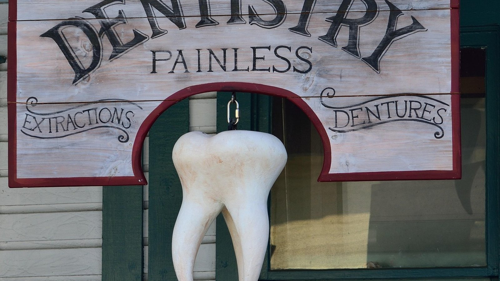 Vývesný štít zubnej ambulancie s veľkým zubom a nápisom Dentures