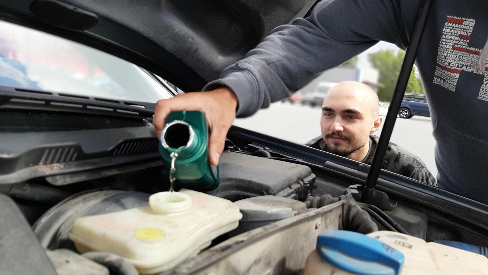Muž dolieva chladiacu kvapalinu do expanznej nádobky v motorovom priestore