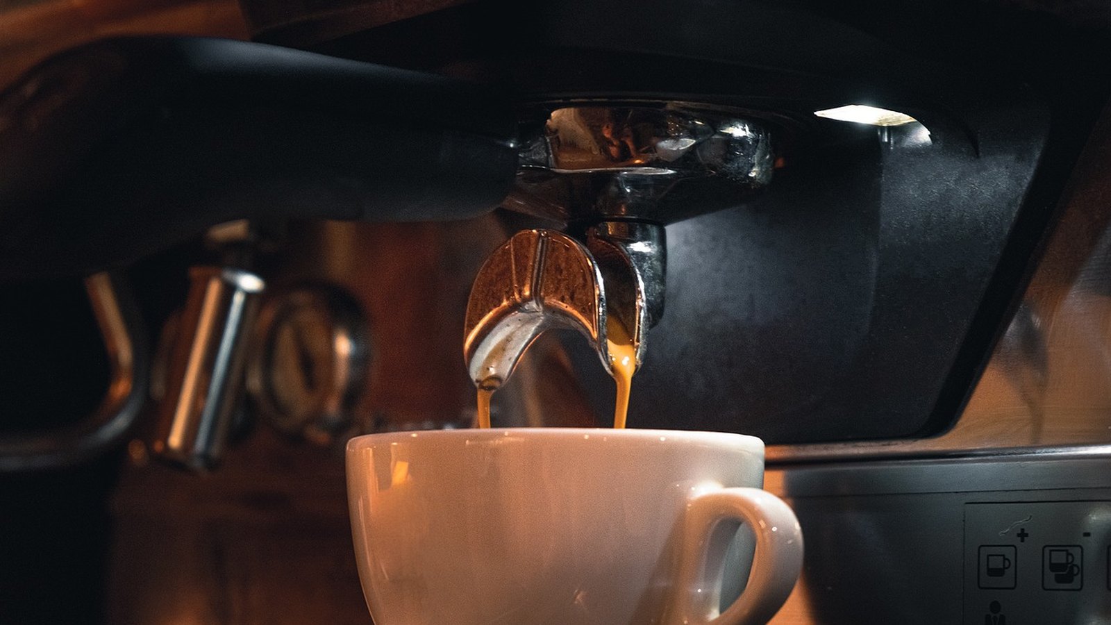 Espresso tečie z kávovaru do bielej šálky